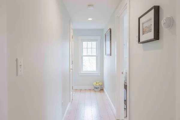 a view of a hallway with wooden floor and a bathroom