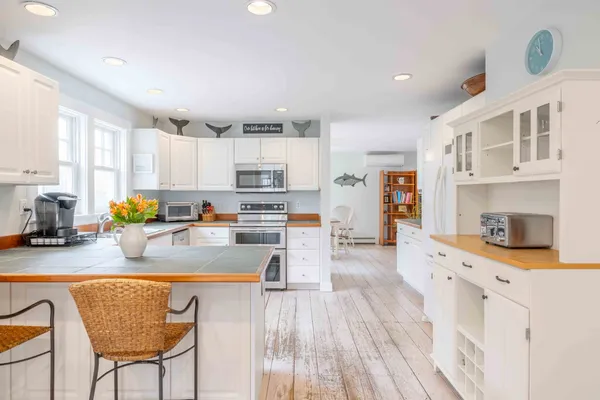 a kitchen with stainless steel appliances granite countertop a refrigerator a stove top oven a sink dishwasher and white cabinets with wooden floor