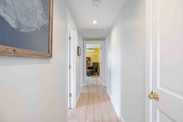 a view of a hallway with wooden floor and a bathroom