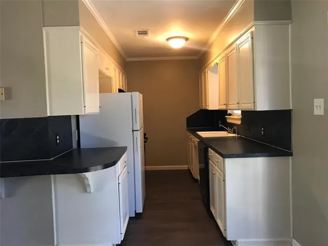 a kitchen with granite countertop a sink and a refrigerator