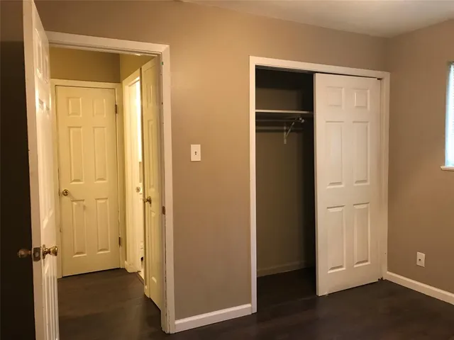 an empty room with wooden floor and closet area