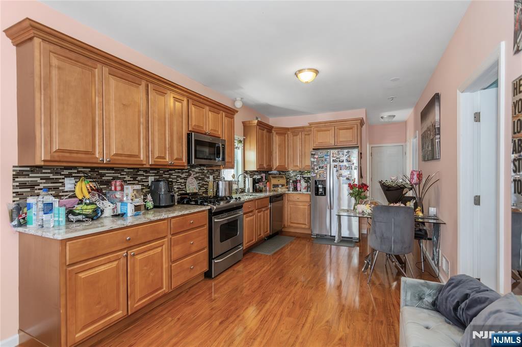 204 Hayward Place Wallington, NJ 07057 - Photo 7 of 39 a kitchen with stainless steel appliances granite countertop wooden floors a stove top oven a sink and dishwasher with wooden floor