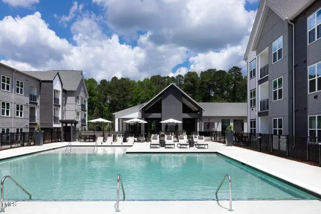 a view of swimming pool with outdoor seating and house in the background