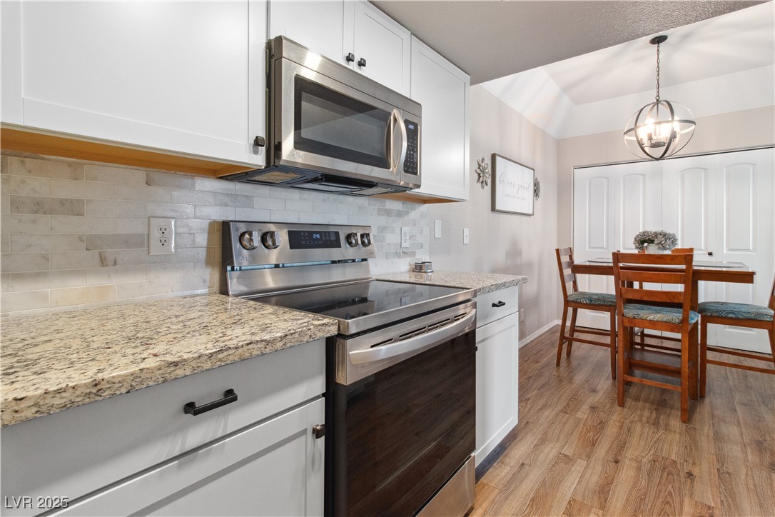 3550 Bay Sands Drive, Unit 2101 Laughlin, NV 89029 - Photo 11 of 49 Closer view of the stainless steel electric stove-top oven, stainless steel microwave, and the Dining Area with beautiful modern hanging light fixture.
