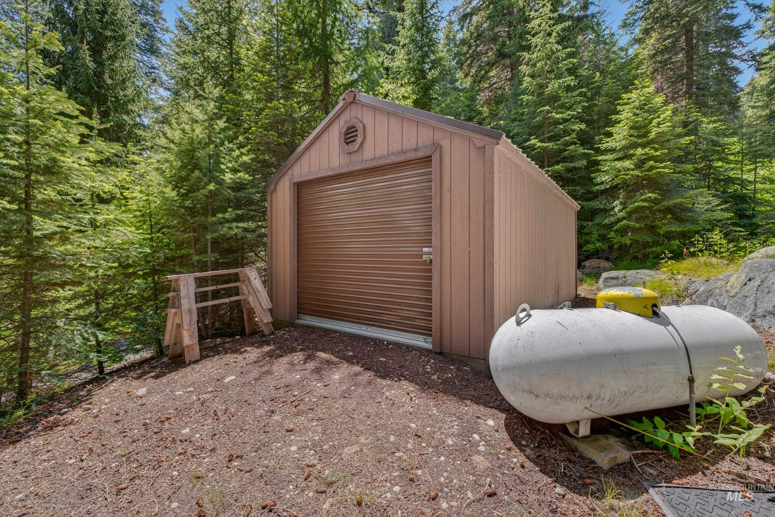 2339 West Mountain Road Donnelly, ID 83615 - Photo 34 of 37 Detached utility shed with a roll-up door, vertical siding, and a gabled roof