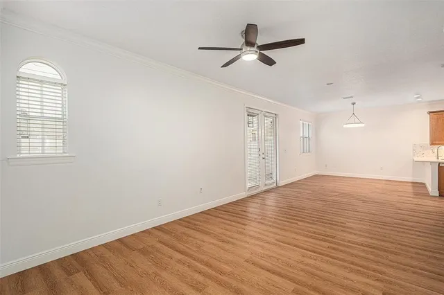 an empty room with wooden floor fan and windows