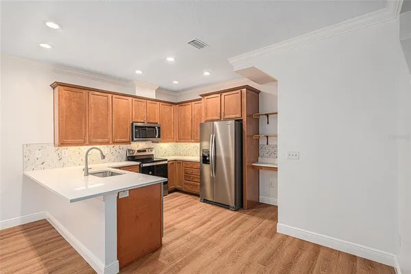 a kitchen with stainless steel appliances granite countertop a refrigerator stove a sink and dishwasher with wooden floor