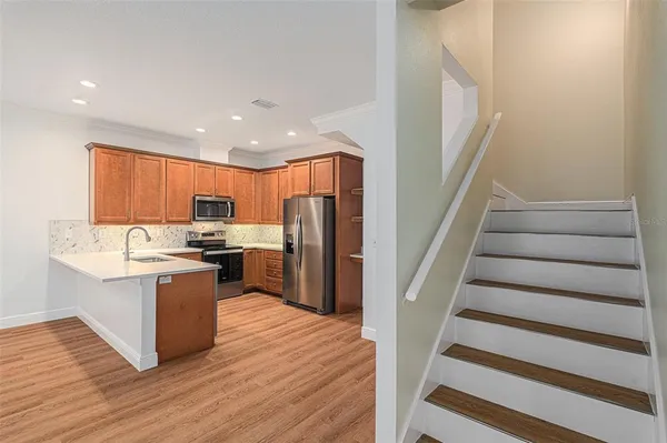 a kitchen with stainless steel appliances kitchen island wooden floors wooden cabinets and entryway