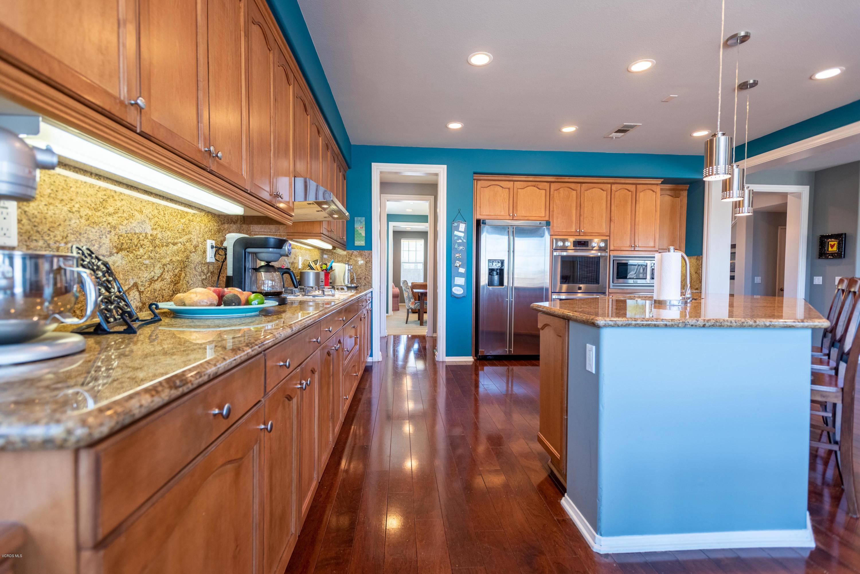 17118 Raindrop Court Riverside, CA 92503 - Photo 22 of 68 a large kitchen with stainless steel appliances kitchen island a large counter top and a view of living room