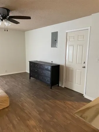 a view of an empty room with cabinet and wooden floor