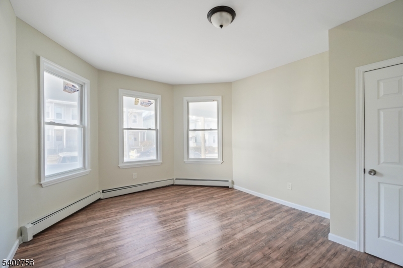 874 South 16th Street Newark, NJ 07108 - Photo 6 of 29 an empty room with wooden floor and windows