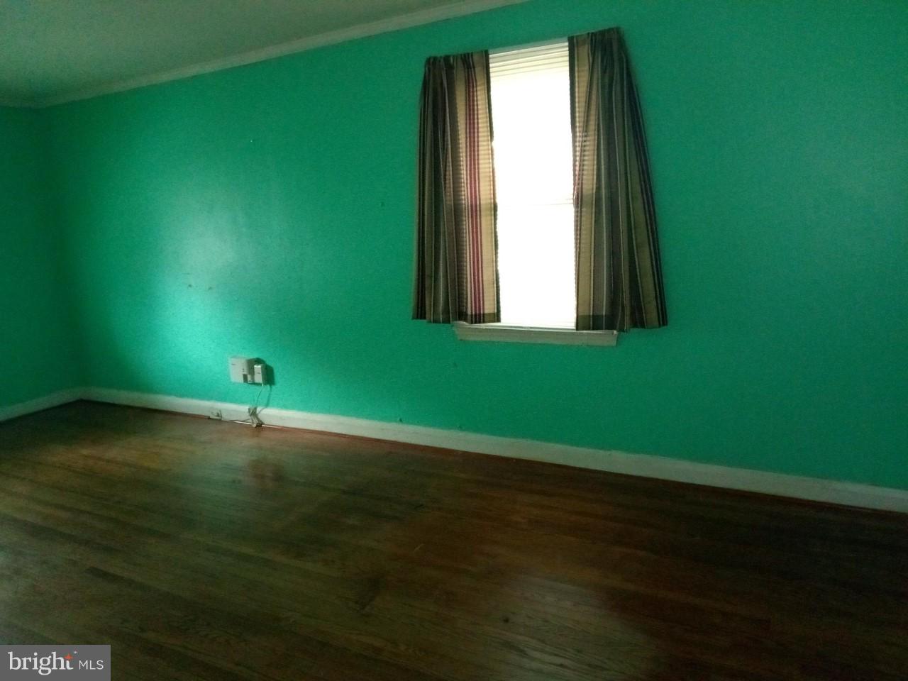 3321 Fairview Road Baltimore, MD 21207 - Photo 5 of 12 an empty room with wooden floor and windows with curtains