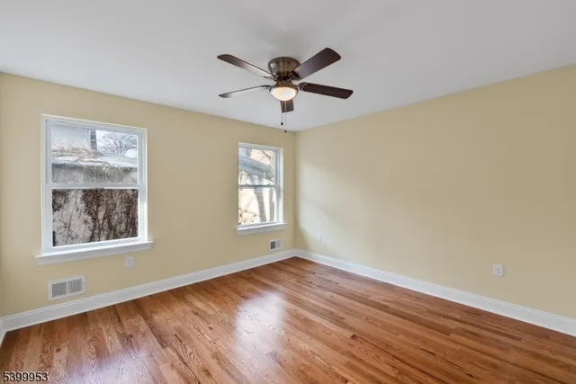 a view of an empty room with window and wooden floor