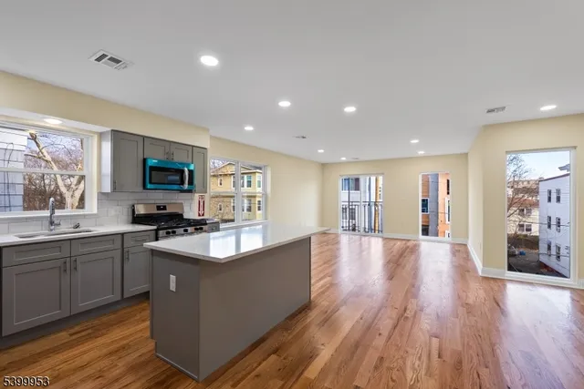 a large kitchen with stainless steel appliances granite countertop a lot of counter space and wooden floors