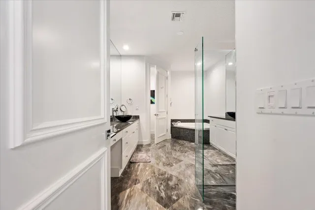 a large white kitchen with granite countertop a stove a sink a refrigerator and white cabinets with wooden floor