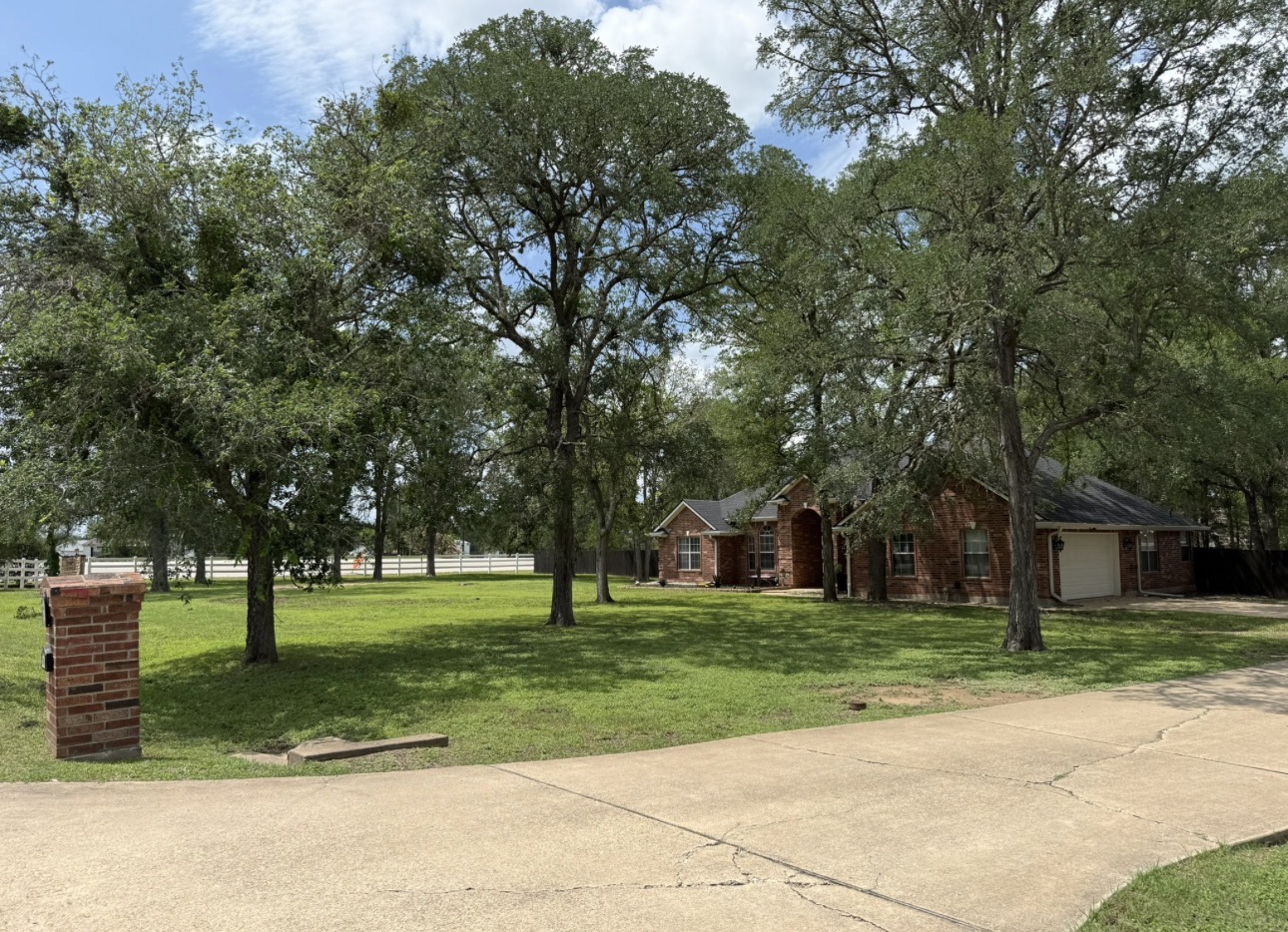 104 Spring Branch Bastrop, TX 78602 - Photo 3 of 32 Mature trees shade this brick residence, offering privacy and a spacious, verdant front yard.