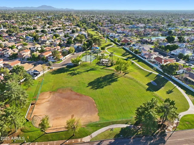 an aerial view of a residential houses with outdoor space and trees