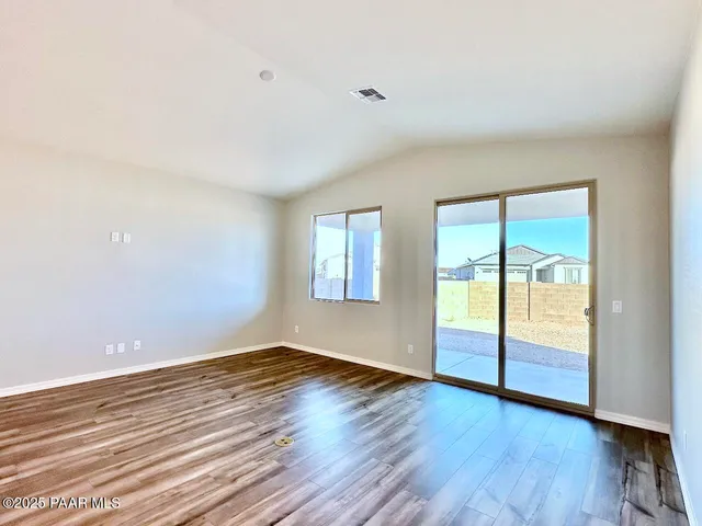a view of an empty room with window and wooden floor