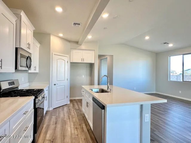 a kitchen with granite countertop white cabinets and stainless steel appliances