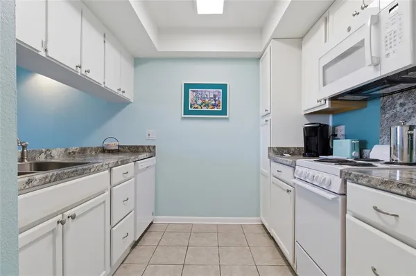 a kitchen with granite countertop white cabinets and white appliances