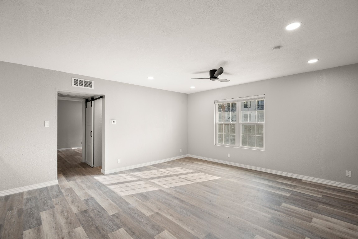 a view of empty room with wooden floor and fan