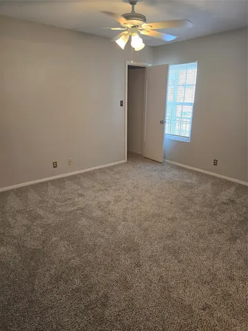 an empty room with windows and chandelier fan