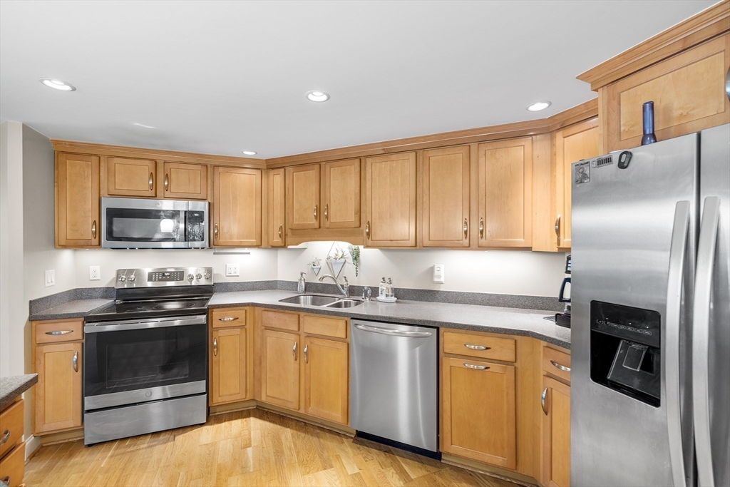 490 Main Street, Unit 215 Northborough, MA 01532 - Photo 11 of 37 a kitchen with stainless steel appliances granite countertop a stove a sink dishwasher a refrigerator and a microwave oven with wooden floor
