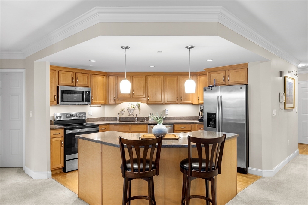490 Main Street, Unit 215 Northborough, MA 01532 - Photo 10 of 37 a kitchen with stainless steel appliances a refrigerator a stove a sink a dining table and chairs