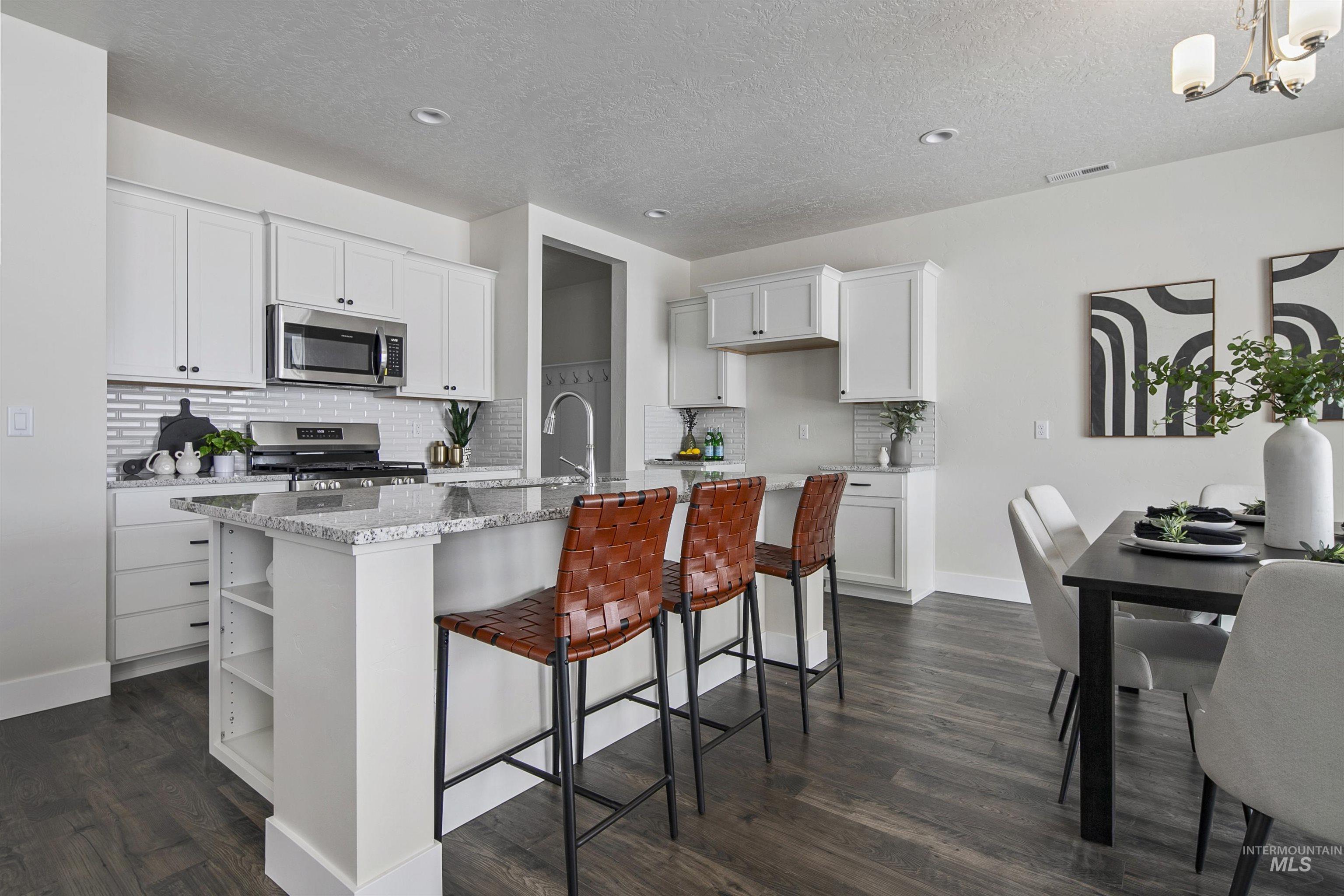 5985 North Backfire Way Meridian, ID 83646 - Photo 12 of 17 Kitchen with light stone counters, white cabinets, a breakfast bar area, decorative backsplash, and an island with sink