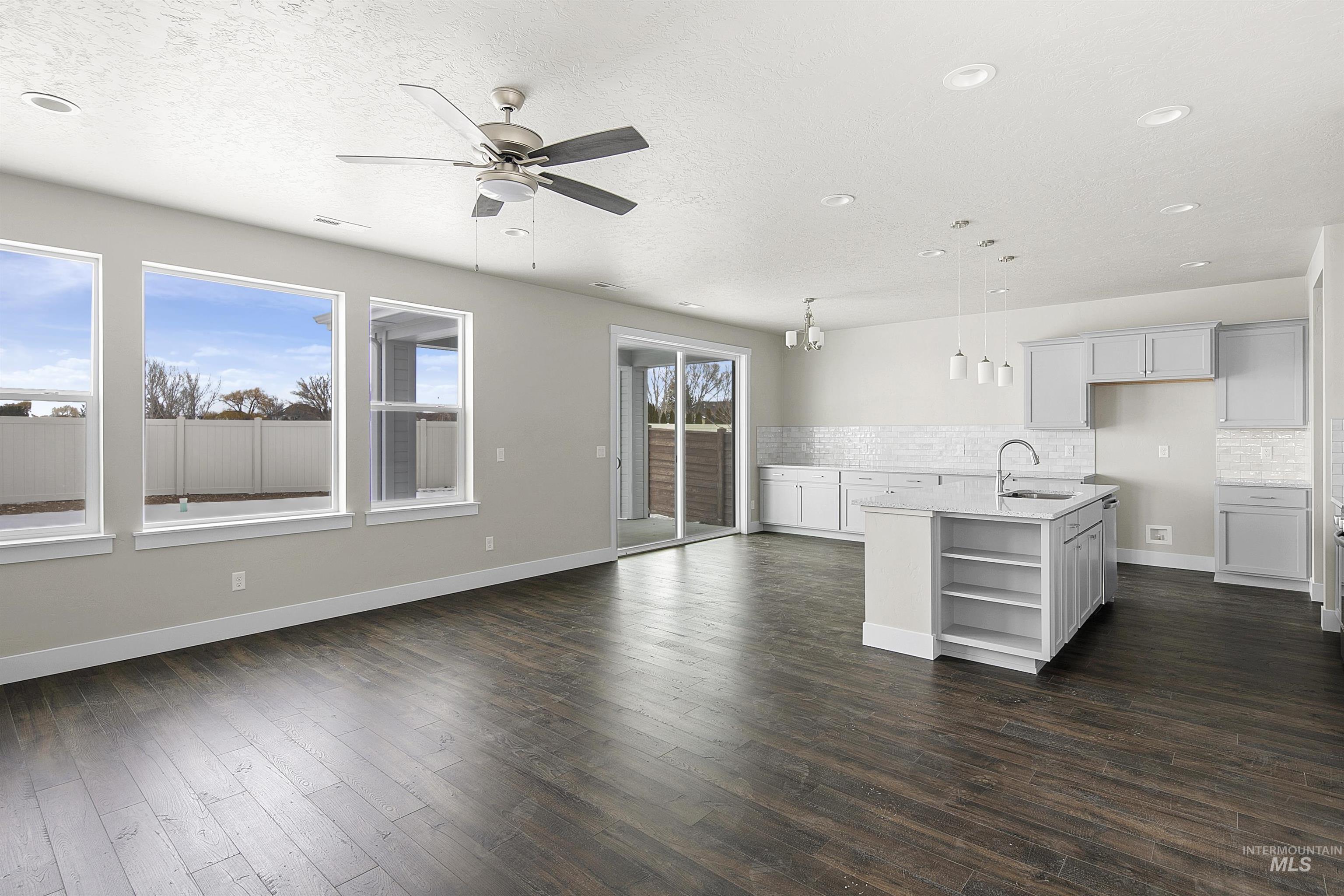 5985 North Backfire Way Meridian, ID 83646 - Photo 3 of 17 Unfurnished living room with dark wood-style floors, a ceiling fan, a textured ceiling, and recessed lighting