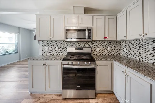 a kitchen with granite countertop white cabinets and stainless steel appliances