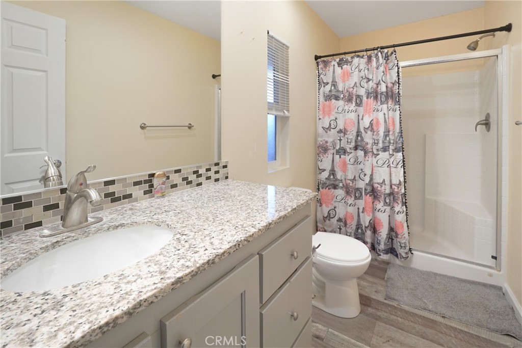 12700 Elliott El Monte, CA 91732 - Photo 9 of 18 a bathroom with a granite countertop sink a toilet and shower curtain