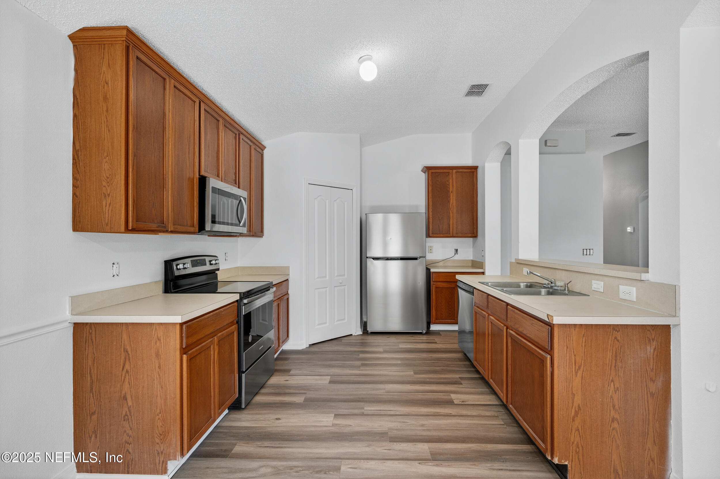 10174 Rising Mist Lane Jacksonville, FL 32221 - Photo 12 of 31 a kitchen with stainless steel appliances granite countertop a stove top oven a refrigerator a sink and dishwasher with wooden floor