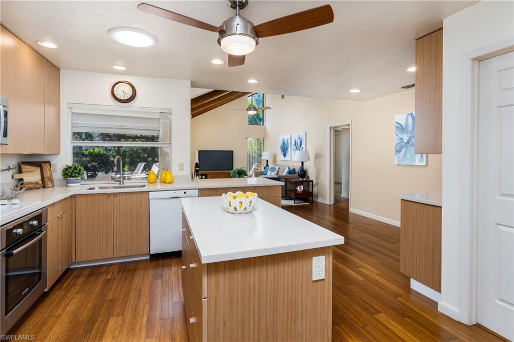 1172 Kings Way Naples, FL 34104 - Photo 19 of 50 a kitchen with stainless steel appliances a center island wooden floor cabinets and a window