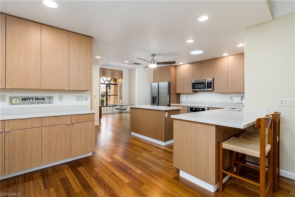 1172 Kings Way Naples, FL 34104 - Photo 22 of 50 a kitchen with stainless steel appliances granite countertop a refrigerator a stove and a wooden floors