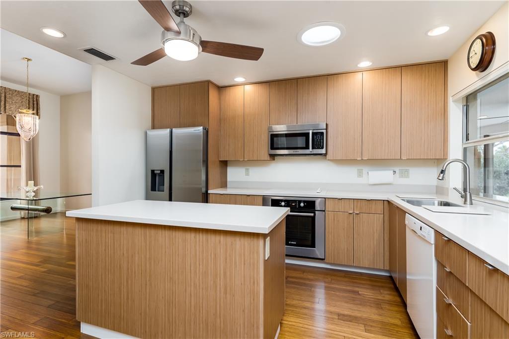 1172 Kings Way Naples, FL 34104 - Photo 23 of 50 a kitchen with stainless steel appliances granite countertop a sink a stove a refrigerator with grey cabinets and wooden floor
