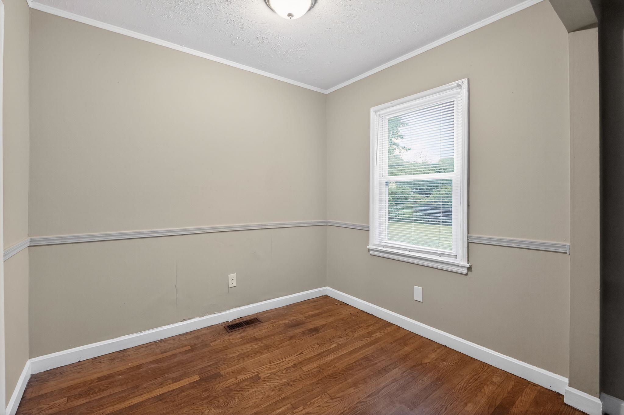 4067 Grantham Road Memphis, TN 38109 - Photo 14 of 34 Spare room featuring dark wood-style flooring, a textured ceiling, and crown molding
