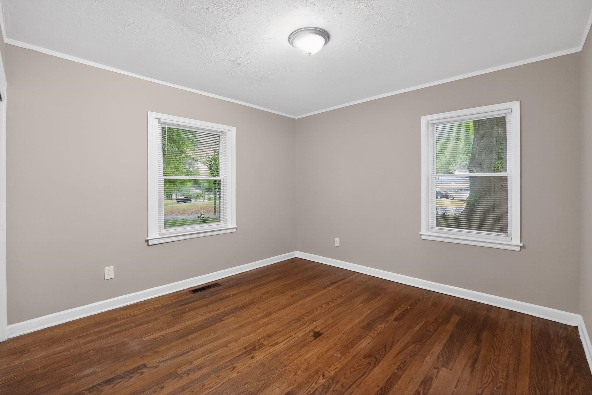4067 Grantham Road Memphis, TN 38109 - Photo 15 of 34 Empty room featuring dark wood-type flooring, ornamental molding, healthy amount of natural light, and a textured ceiling