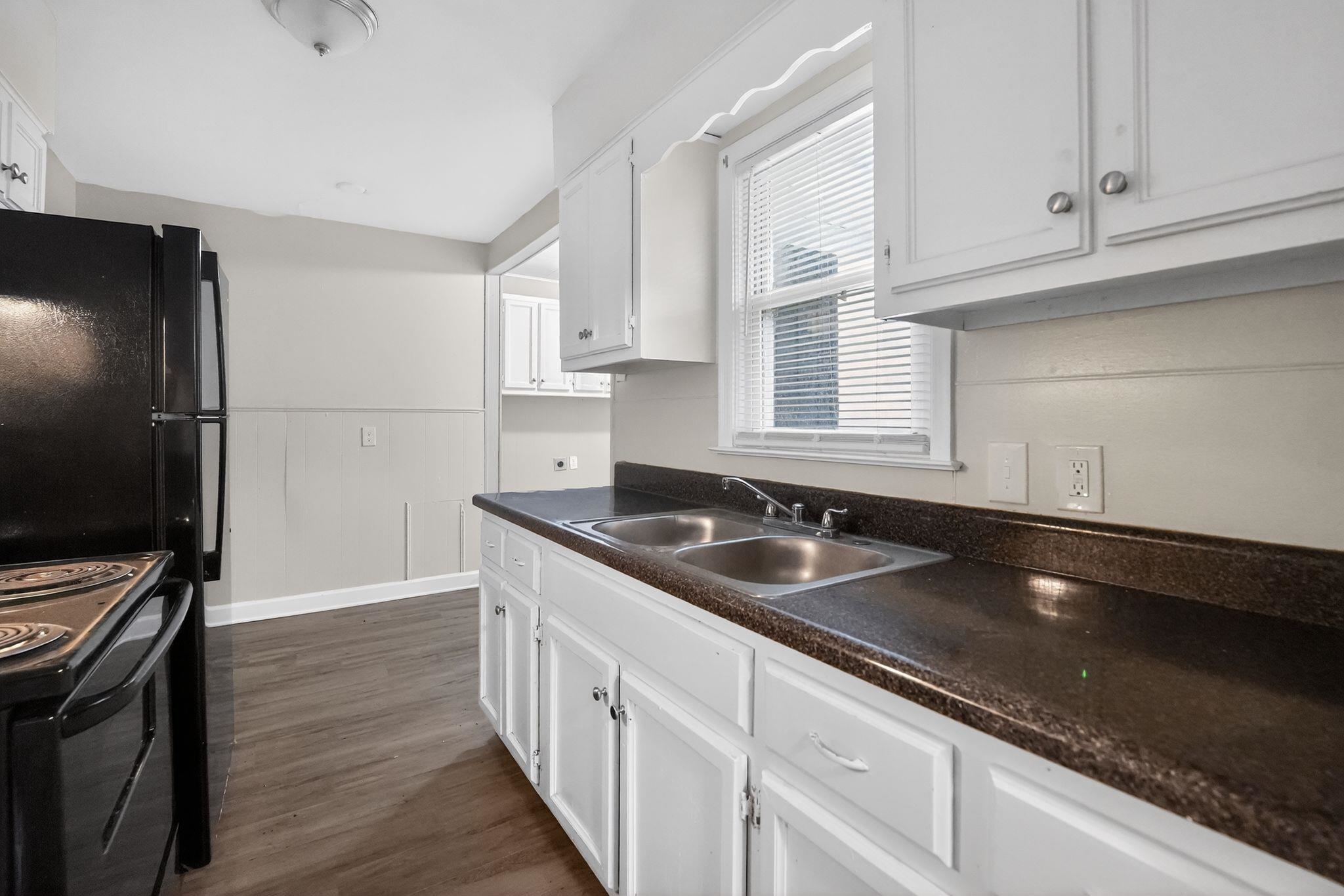 4067 Grantham Road Memphis, TN 38109 - Photo 21 of 34 Kitchen with white cabinets, a wainscoted wall, dark wood-style flooring, dark countertops, and black range with electric cooktop