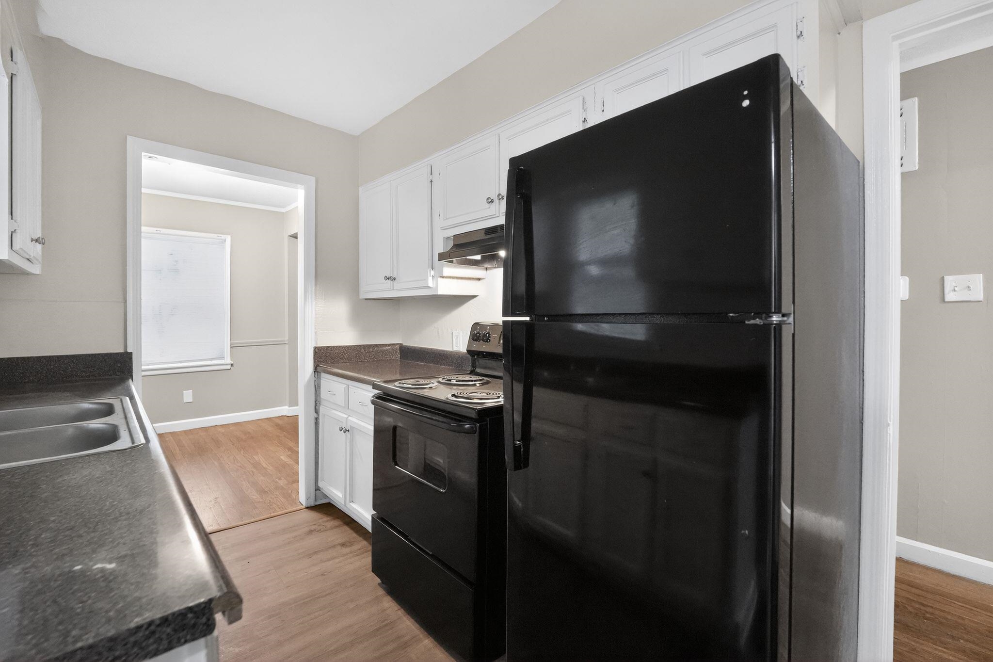 4067 Grantham Road Memphis, TN 38109 - Photo 22 of 34 Kitchen with dark countertops, black appliances, white cabinets, and light wood-type flooring
