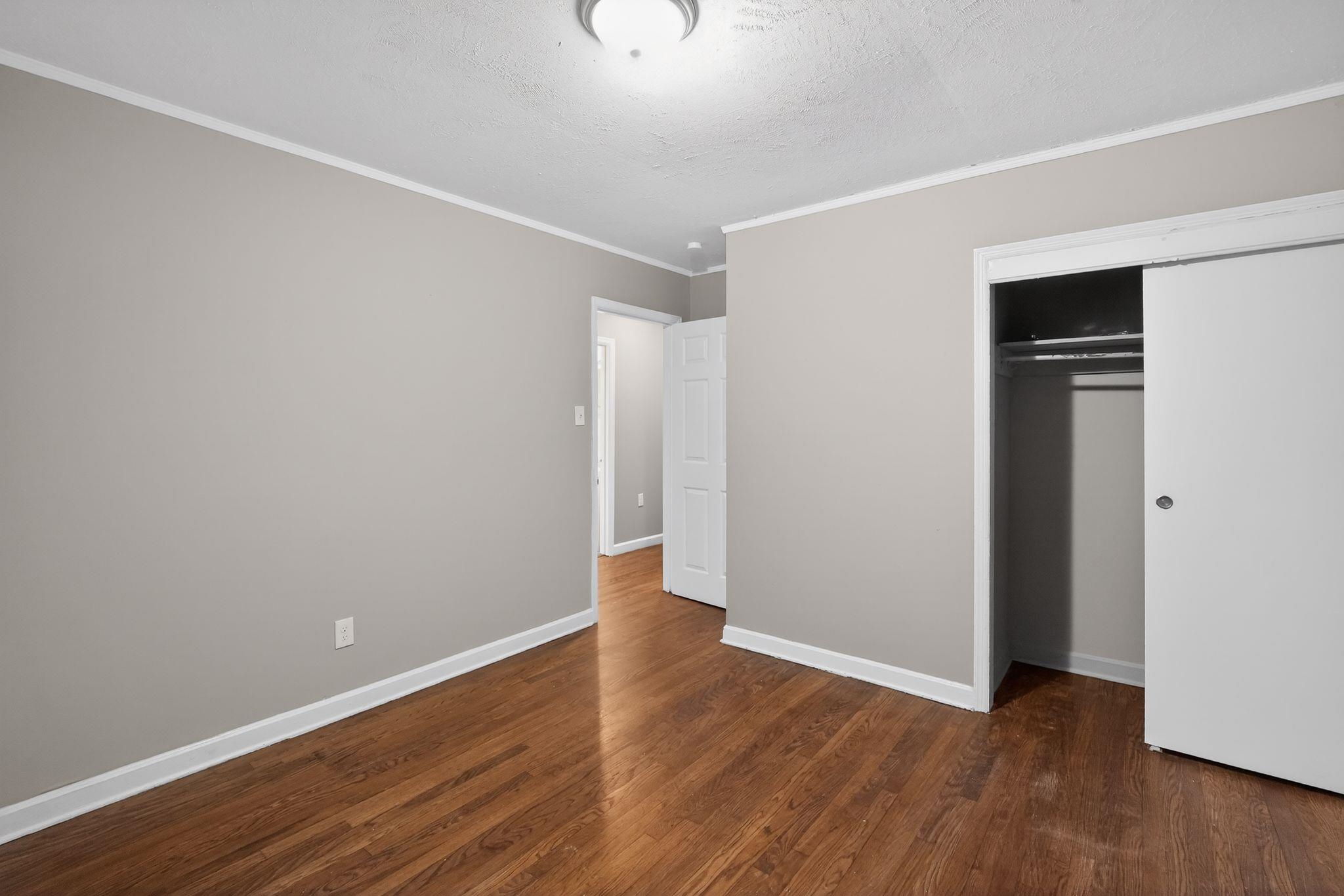 4067 Grantham Road Memphis, TN 38109 - Photo 26 of 34 Unfurnished bedroom with crown molding, dark wood finished floors, a textured ceiling, and a closet