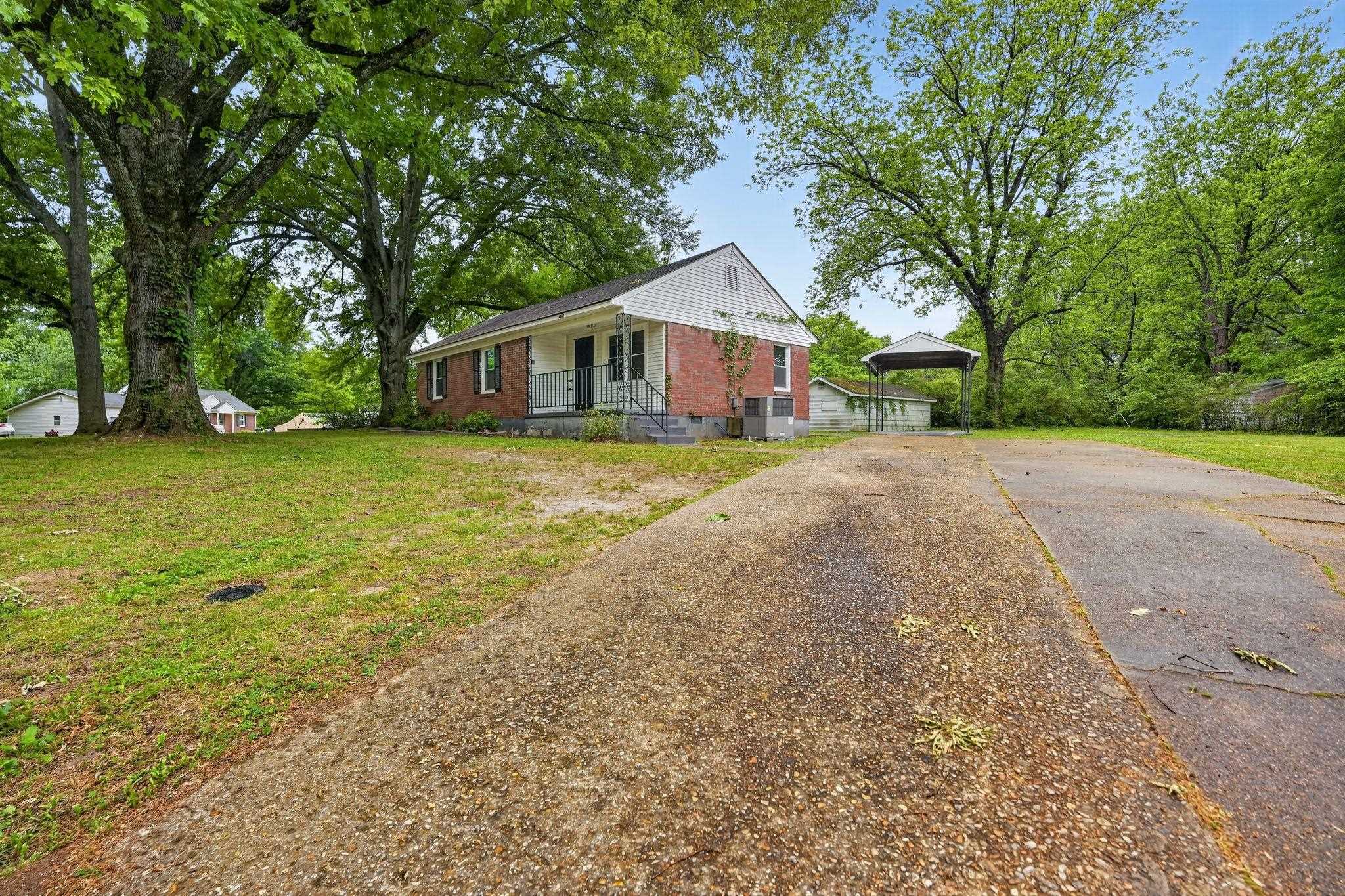 4067 Grantham Road Memphis, TN 38109 - Photo 3 of 34 View of front of property with brick siding, a front yard, asphalt driveway, and view of wooded area