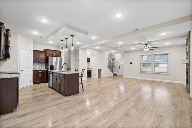 an open kitchen with wooden floor and stainless steel appliances
