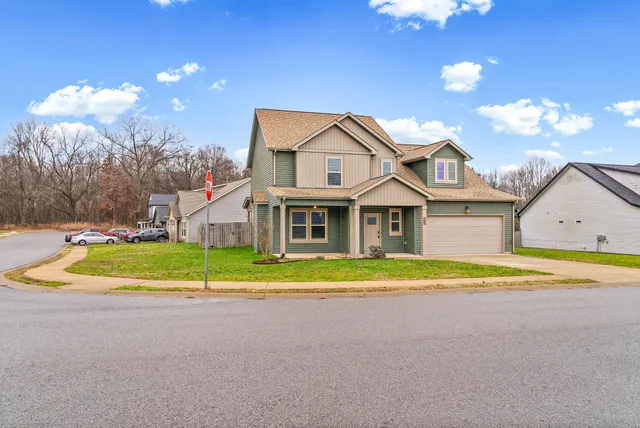 a view of house with outdoor space and large trees
