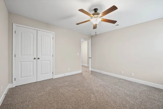an empty room with a hallway and a ceiling fan