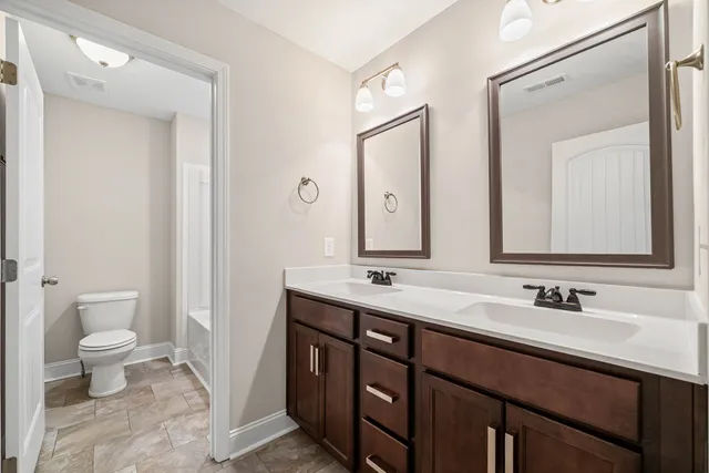a bathroom with a double vanity sink toilet and mirror