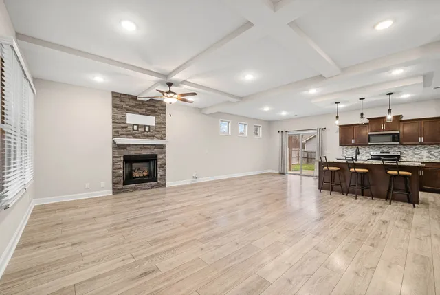 a view of an empty room with kitchen and a window