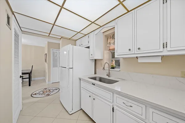 a kitchen with white cabinets and refrigerator