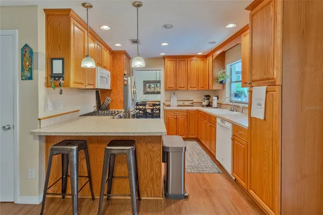 a kitchen with stainless steel appliances granite countertop wooden cabinets a dining table and chairs