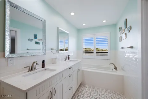 a bathroom with a sink a bathtub a mirror a vanity and a bathtub